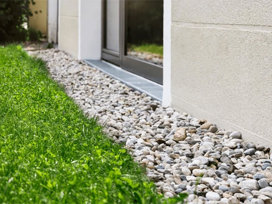 French drain installation integrated with a residential retaining wall and patio in Orlando to manage yard drainage.