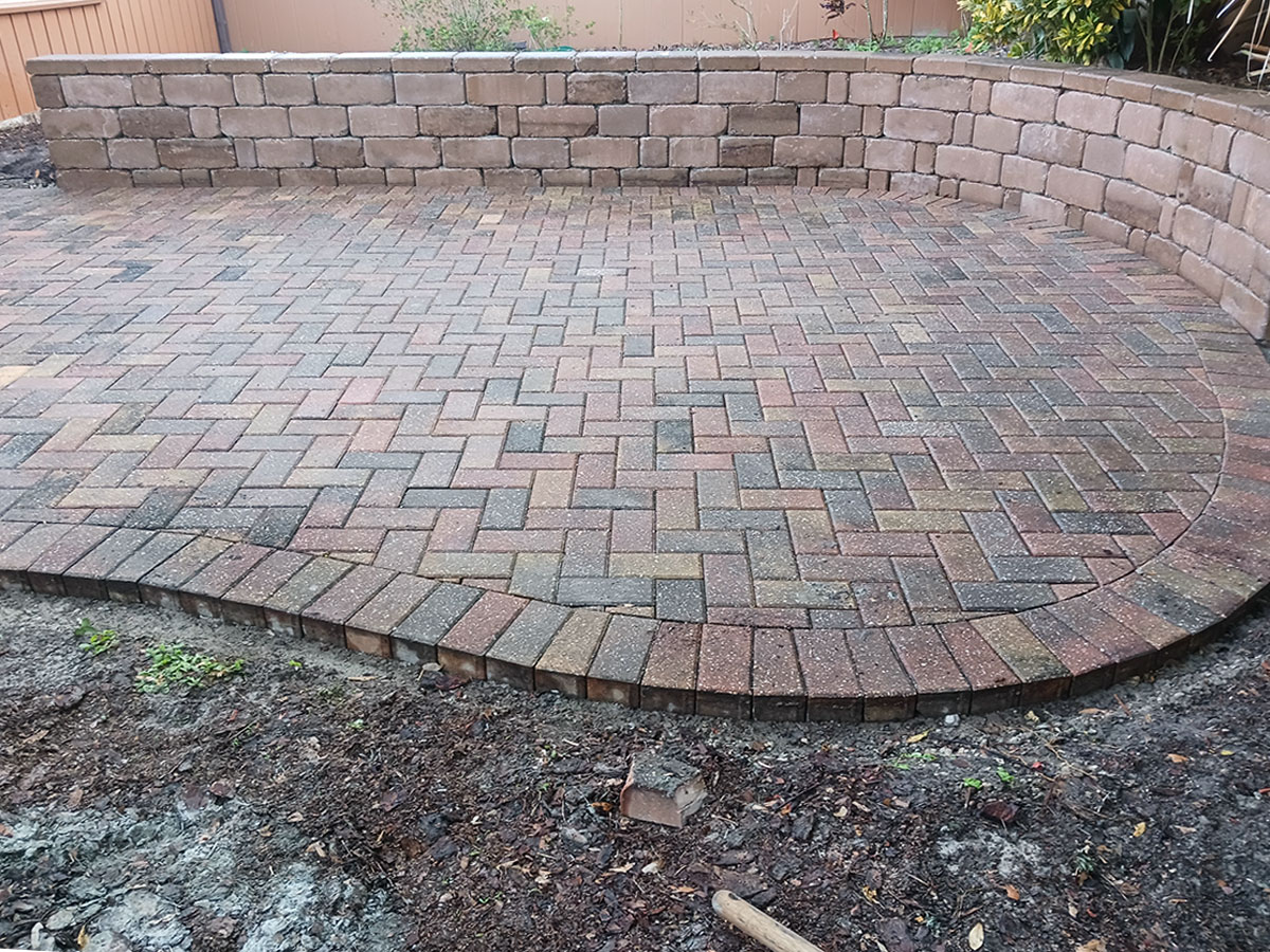 Low segmental retaining wall integrated with a paver patio — common in Orlando-area residential landscapes where grade changes and drainage must be properly managed.