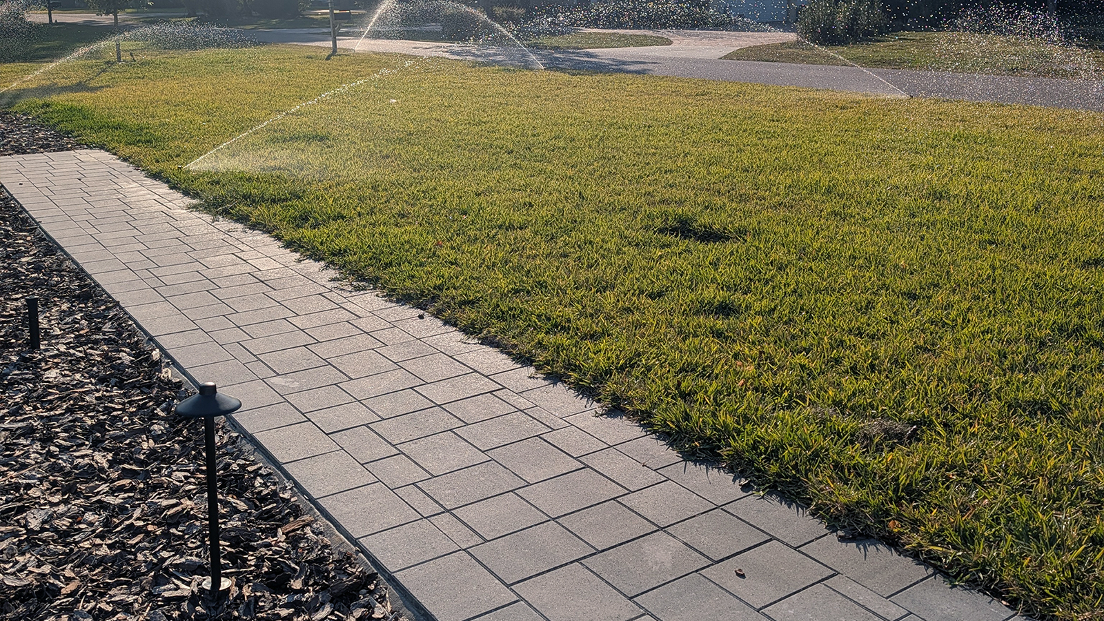 Paver walkway installation in Lake Mary Florida with landscape edging and lawn irrigation system in background